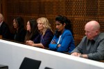 a group of people sitting in a row with their arms crossed