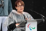 a woman in a wheelchair stands at a podium with a paralympic logo on it