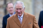 a man in a tan coat and tie smiles for the camera