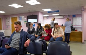 a group of people are waiting in a waiting room under a sign that says reception