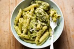 a bowl of pesto pasta with a fork in it