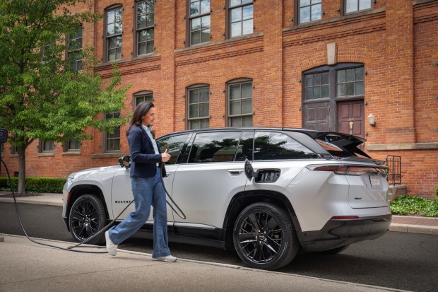 a woman is charging a white jeep with a charger