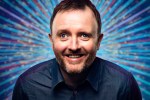 a man with a beard is smiling in front of a blue background